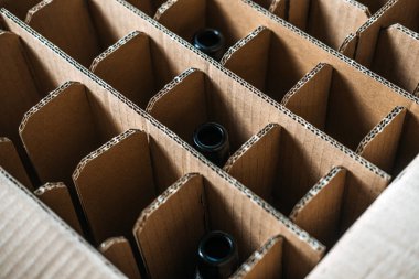 Bira şişeleri için tasarlanmış yuvarlak karton kutunun üst açılı görüntüsü, güvenli içecek taşımacılığı için sürdürülebilir ambalaj uygulamalarını vurguluyor. Nakliyedeki çevre dostu malzemelere odaklanın