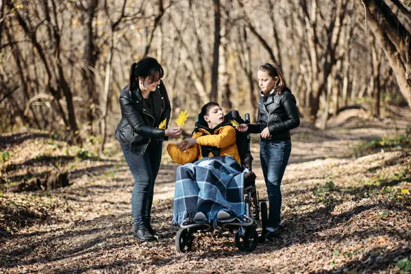 stock image A mother enjoys a peaceful forest walk with her child, who is in a wheelchair. The image highlights the therapeutic benefits of nature, disability inclusion, and the use of adaptive equipment for