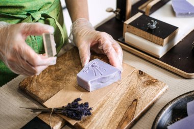 El yapımı lavanta sabununa çiçek pulu bastıran eller. Doğal cilt bakımına, organik sabun yapımına ve sürdürülebilir yaşam pratiklerine odaklanın..