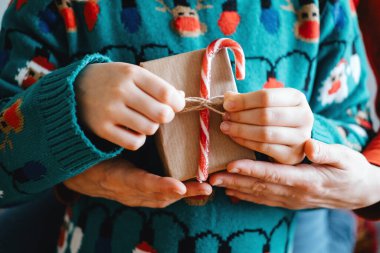 Bir anne ve kız Noel hediyesini tutarken kucaklaşır, evde birlikte uzun süreli tatil anıları yaratmanın sıcaklığını ve neşesini yakalar..