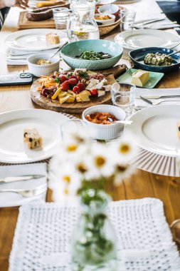 Çiftlikten sofraya taze şarküteri, çiçek süsü ve sanatsal yemekleri olan, doğal yaşam ve gurme sadeliğini gösteren kırsal yemek masası..