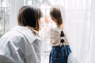 Bir anne, çocuklarının burnuna nazikçe dokunarak neşeli ve samimi bir aile anını yakalar. Bağlanmayı, çocukluğu ve annelik bakımını vurgular.