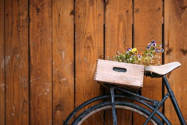 Kırsal ahşap duvarlara karşı çiçeklerle dolu ahşap sandıklı klasik bisiklet, çevre dostu bahçe ve sürdürülebilir dekorasyon.
