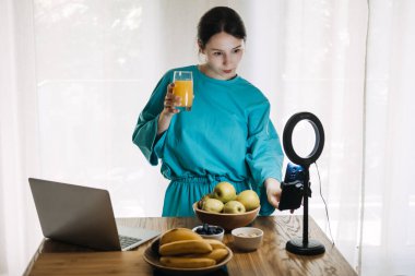 Yüzük ışığı ve taze ürünlerle çekim yapan bir kadın. Evde bloglama, kişisel markalaşma ve içerik oluşturma eğilimleri