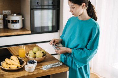 Sıcak bir mutfakta taze yemekler hazırlayan bir kadın. Sağlıklı yaşam, dikkatli harcamalar ve maliyetli beslenme için bütçe ayırmak