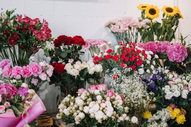Çiçekçide gül, ayçiçeği, karanfil ve ortanca içeren taze zanaatkar buketleri sergileniyor. Dükkandaki yerel hareketleri, küçük işletme eğilimlerini ve el yapımı çiçekleri yansıtıyor.