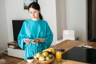 Kadın mutfak tezgahında taze meyve suyu ve meyve suyunun yanında Amerikan doları sayıyor. Para yönetimi, kişisel finans, refah için bütçe, sağlıklı yaşam tarzı ekonomisi. Yüksek kalite fotoğraf