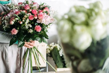 Çiçekçi stüdyoda tamamlanmış pembe güller, merhem ve bebek nefesi tutuyor. Çiçekçi çalışmaları, zanaatkar çiçekçilik, botanik tasarımı, ekolojik yaratıcılık. Yüksek kalite fotoğraf