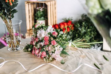 Çiçekçide, kraft kağıdının üzerinde duran el yapımı pembe çiçek buketi. Sosyal medya pazarlaması, çiçekçi markası, el yapımı buket, yaratıcı çalışma alanı. Yüksek kalite fotoğraf