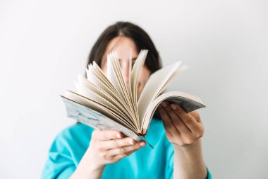 Genç bir kadın, önünde sayfaları titreyen açık bir günlük tutuyor. Öz-yansıma, terapi olarak günlük tutma, bilinçli rutinler, analog yaratıcılık. Yüksek kalite fotoğraf