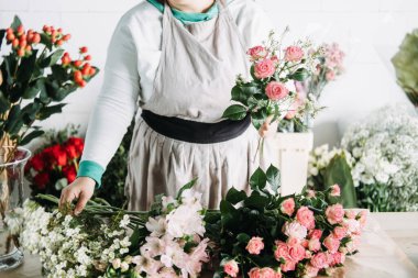 Çiçekçi, pembe zambaklar ve gülleri stüdyoda çalışan çiçeklere yerleştirir. Kadınların sahip olduğu iş, çiçekçi, bağımsız yaratıcı, yaratıcı girişimci..