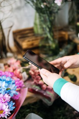 Çiçekçi, çiçekçide dijital mağazayı yönetmek için akıllı telefon kullanıyor. Ecommerce çiçekçiliği, küçük işletme teknolojisi ve mobil pazarlama eğilimlerini yansıtır.