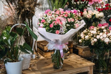 Bir çiçekçide sergilenen, peçete ve kurdeleye sarılı pembe ve beyaz çiçeklerden oluşan bir buket. Çiçek pazarlama, romantik hediye, küçük işletme perakendecisi, botanik tasarımı. Yüksek kalite fotoğraf