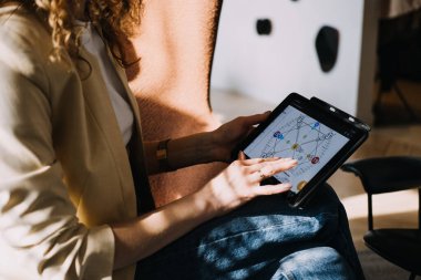 Numerolog bir tablet kullanarak güneşli bir odada dijital sayıbilim tablosunu yorumluyor. Modern numeroloji, metafizik teknolojisi, sezgisel tasarım, ruhani analitik..