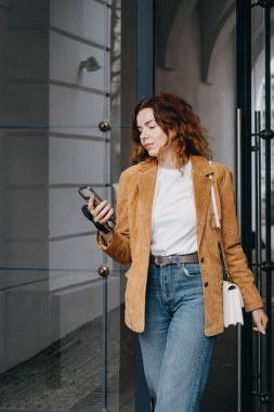 Teknoloji meraklısı bir kadın modern binanın dışında mobil yaşam tarzıyla ilgileniyor. Akıllı telefon alışkanlıkları, mobil verimlilik ve dijital davranış...