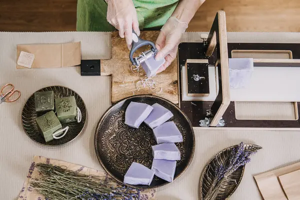Şifalı otlar ve ambalaj malzemeleriyle çevrili el yapımı lavanta sabunlarını rafine eden bir kadının en iyi görüntüsü. Botanik sağlık, bitkisel cilt bakımı, temel yağlar, sakinleştirici aromaterapi. Yüksek kalite fotoğraf