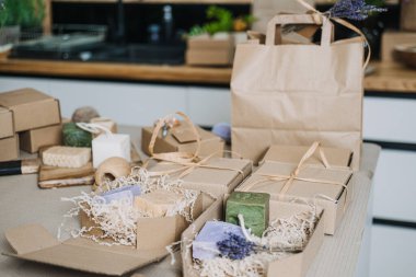 Doğal el yapımı sabun, karton ambalaj ve masa üstünde çevre dostu hediye paketleme aletleri koleksiyonu. Sürdürülebilirlik, küçük işletme desteği, zanaatkarlık, sıfır atık ambalaj.