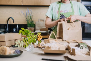 İnsan doğal sabunları Kraft ambalajına sarar. Ev mutfağında küçük bir iş için. El yapımı ürün ambalajlama, yaratıcı süreç, DIY iş görselleri, ev bazlı iş. Yüksek kalite fotoğraf