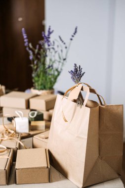 Doğal sabun hediye kutuları ve kraft çantaları çiçek desenli bir masada düzenlenir. El yapımı hediyeler, tatil hazırlığı, doğal cilt bakımı hediyesi, sağlık hediyesi kutusu. Yüksek kalite fotoğraf
