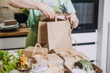 İnsan doğal sabunları Kraft ambalajına sarar. Ev mutfağında küçük bir iş için. El yapımı ürün ambalajlama, yaratıcı süreç, DIY iş görselleri, ev bazlı iş. Yüksek kalite fotoğraf