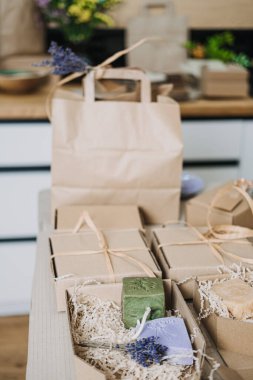 Kraft poşetleri ve kurutulmuş lavantanın yanına yerleştirilmiş el yapımı sabunlarla dolu sürdürülebilir hediye kutuları. Yeşil işletme değerleri, çevre dostu ambalaj, plastiksiz markalaşma, küçük toplu sunum. 
