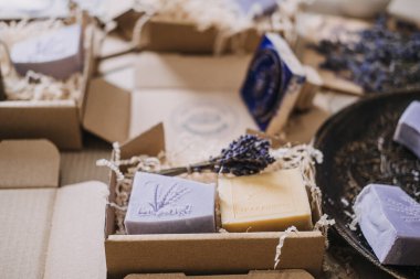 Lavanta ve sarı el yapımı sabunlar. Damgalı amblemler, kraft kutularına ve kurutulmuş çiçeklere konmuş. El yapımı sabun, el yapımı markalaşma, logo damgası, küçük seri üretim. Yüksek kalite fotoğraf