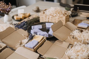 El yapımı lavanta sabunları, Kraft kutularına doldurulmuş, rahat bir çalışma alanında dilimlenmiş dolgu malzemesi ile. Ev yapımı iş, el yapımı cilt bakımı, küçük seri üretim, çevre dostu ambalaj. Yüksek kalite fotoğraf