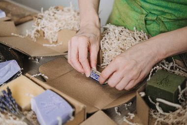 Lavanta çubukları ve doğal dolgu malzemeleriyle çevrili ambalaj sırasında Kraft sabun kutusunu damgalar. Ürün özelleştirme, el yapımı cazibe, sabun imalatçısı markalaşması, yaratıcı ürün kimliği. Yüksek kalite