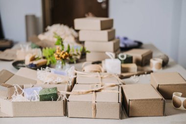 El yapımı sabunlar ve doğal dolgular içeren Kraft Spa hediye kutularıyla dolu bir masa. Spa hediye kutusu, el yapımı sağlık ürünleri, sakinleştirici ritüeller, stres atma hediyeleri. Yüksek kalite fotoğraf