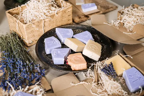 Kurutulmuş lavanta ve kraft ambalajlı bir tabakta çeşitli el yapımı sabunlar sergileniyor. Lavanta sabunu, doğal cilt bakımı, gerekli yağlar, botanik öz bakım. Yüksek kalite fotoğraf