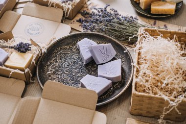 Kraft kutuları ve kurutulmuş dolgu malzemeleriyle çevrili dekoratif bir tabakta lavanta sabunları. Sürdürülebilir sabun, eko-bilinçli ürünler, yeşil ambalaj, plastiksiz yaşam tarzı. Yüksek kalite fotoğraf