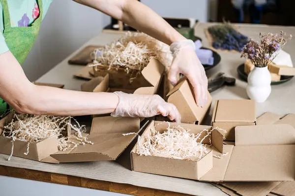 Eldivenli eller yeşil ve lavantalı sabunları bir Kraft hediye kutusuna koyuyor. Dikkatli alışveriş, yavaş yaşam, etik üretim, bilinçli tüketici. Yüksek kalite fotoğraf