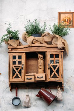 Çuval bezine sarılı otlaklarla, küçük poşetlerle, eski mutfak gereçleriyle ve kırsal tablolarla dekore edilmiş ahşap bir dolap. Cottagecore dekoru, pastoral estetik, sıcak kırsal alan. Yüksek kalite