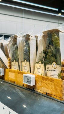 Dijital fiyat etiketleriyle süpermarket rafında sergilenen defne yaprakları ve kekik gibi önceden paketlenmiş Fransız otları. Lyon, Fransa - 19 Ağustos 2025. Yüksek kalite fotoğraf