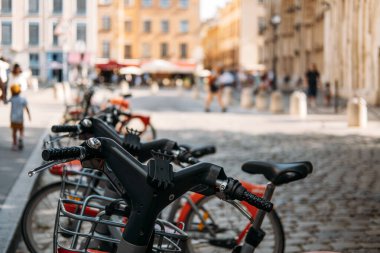 Arka planda bulanık şehir hayatı olan kaldırım taşı caddesinde ortak bisiklet sıraları. Kentsel sürdürülebilirlik, aktif ulaşım, arabasız bölge, düşük emisyon seyahati. Yüksek kalite fotoğraf