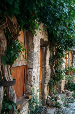 Duvarda büyüyen ahşap panjurları ve asmaları olan eski taş bir ev. Yavaş seyahat, kırsal yaşam tarzı, miras koruma, kırsal kaçış. Yüksek kalite fotoğraf