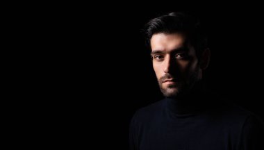 Düşünceli, genç sakallı yakışıklı adam portresi çekici, sakallı, kendine güvenen, bir şeyler planlayan, boş alana bakan, karanlık odada düşünen, kendine güvenen, kameraya bakan havalı adam. 