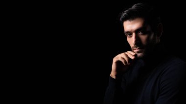 Yakışıklı genç sakallı adamın portresini yapmayı planlarken çekici sakallı, kendine güvenen, planlayan ve kameraya bakan karanlık odada düşünen zeki bir adam.