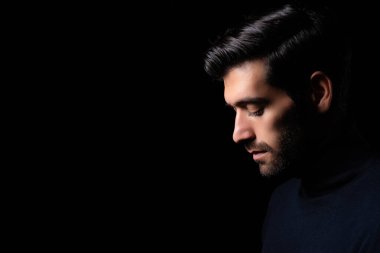 Sakallı adam karanlık odada başını eğ. Adam siyah arka plana yan gözle bakar. Ciddi depresyon ve kasvetli iş adamı gözlerinden ve umutsuz depresyondan başka bir şey görmez.