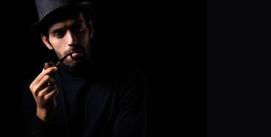 Dedektif ya da casus adam pipo içiyor yakışıklı genç sakallı adam pipo içiyor kafasını çeviriyor ve karanlık oda modası ve modaya uygun bir şeyler planlıyor.