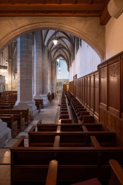 Empty wooden pews or chairs inside Gothic, medieval church in Europe. Wide angle, no people.