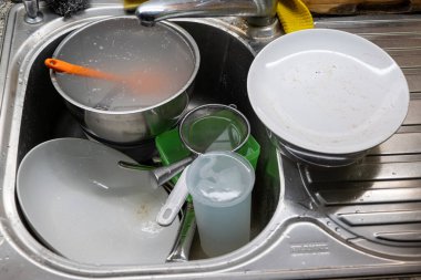 Mutfak lavabosunda kirli bulaşık ve çatal bıçak yığını. Üst manzara, insan yok.