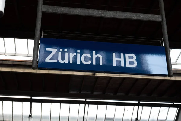 Large blue sign or plaque reading of Zurich HB train main station. Low angle view, no people.