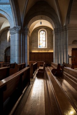 Güneş ışığı boş ahşap kilise sıralarına vuruyor. Geniş açı görünümü, insan yok..