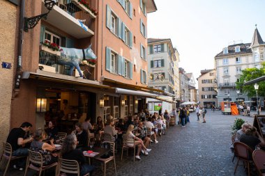 31-05-2023 Zürih, İsviçre. Turistler tarihi şehir merkezindeki restoranların terasında yemek yiyorlar..