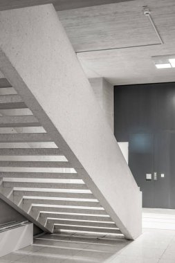 Boş bir kamu binasının koridorundaki beton merdivenler. Modern mimari, parlak iç mekan, insan yok..