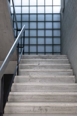 Boş bir kamu binasının koridorundaki beton merdivenler. Modern mimari, parlak iç mekan, insan yok..