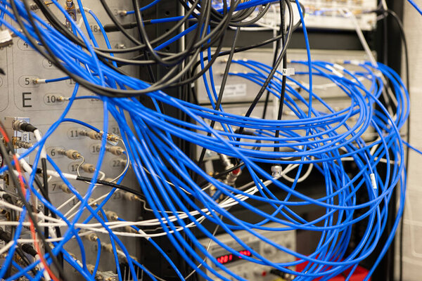 Грязные голубые электрические кабели, подключенные к промышленным лабораторным устройствам, нет людей.