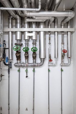Endüstriyel boyutta duvar monte edilmiş su boruları. Büyük boş oda, insan yok.