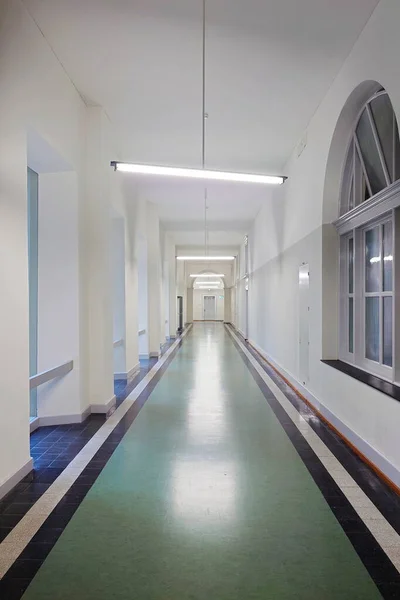 Long empty public building corridor or hallway. Wall and ceiling mounted light, no people